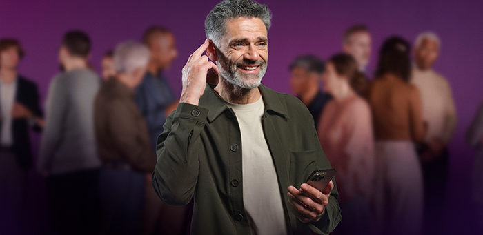 Mann benutzt Smartphone-App zur Hörgeräte-Einstellung